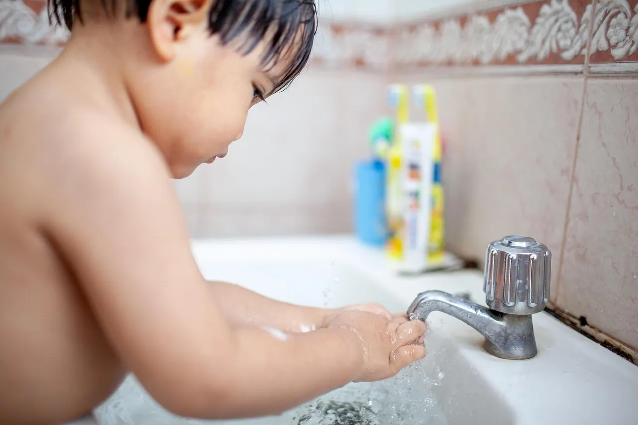 Jeune enfant qui se lave les mains au lavabo